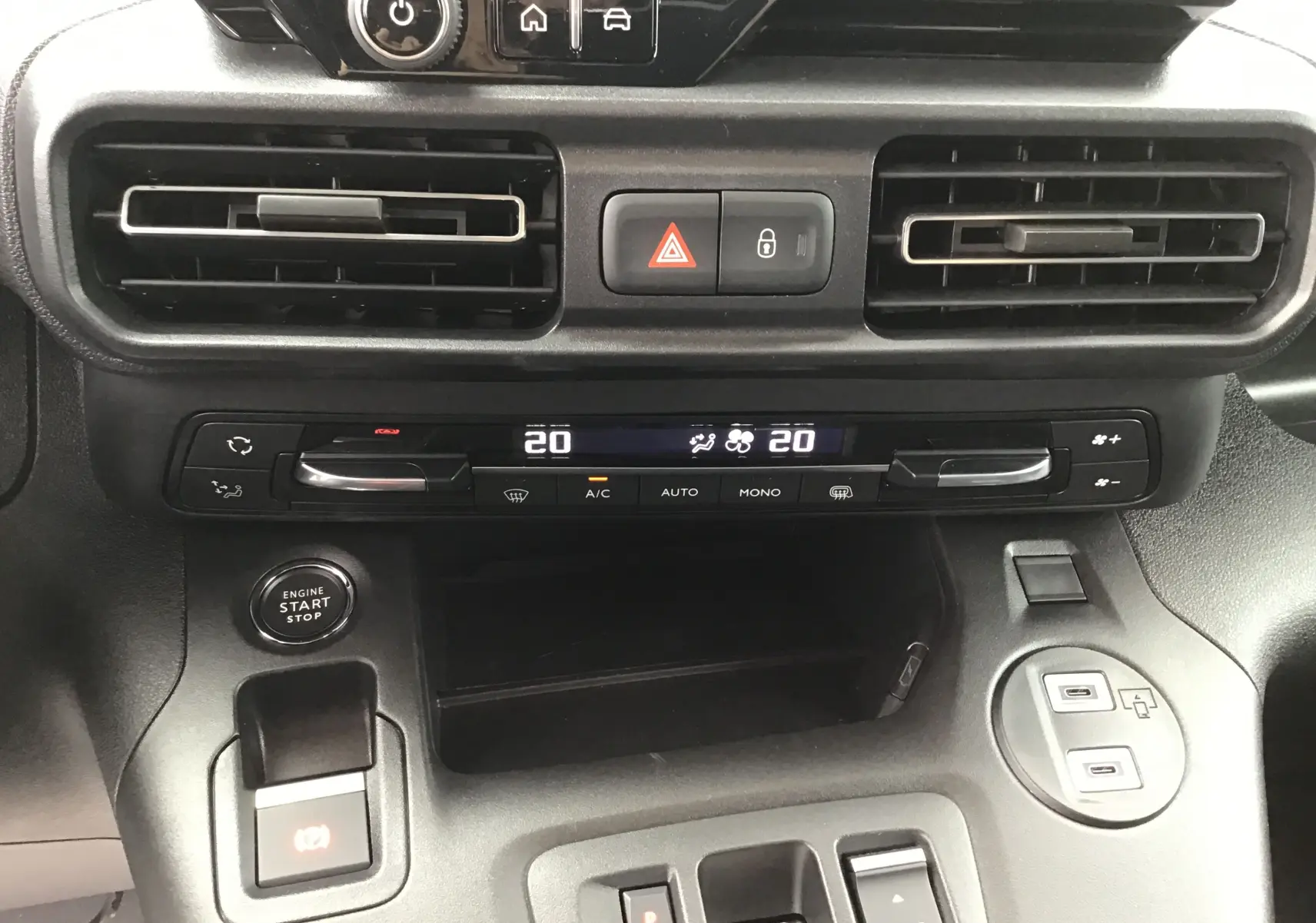 Vue rapprochée du tableau de bord noir du Peugeot Partner 2026, avec commandes climatisation digitale et bouton start/stop.