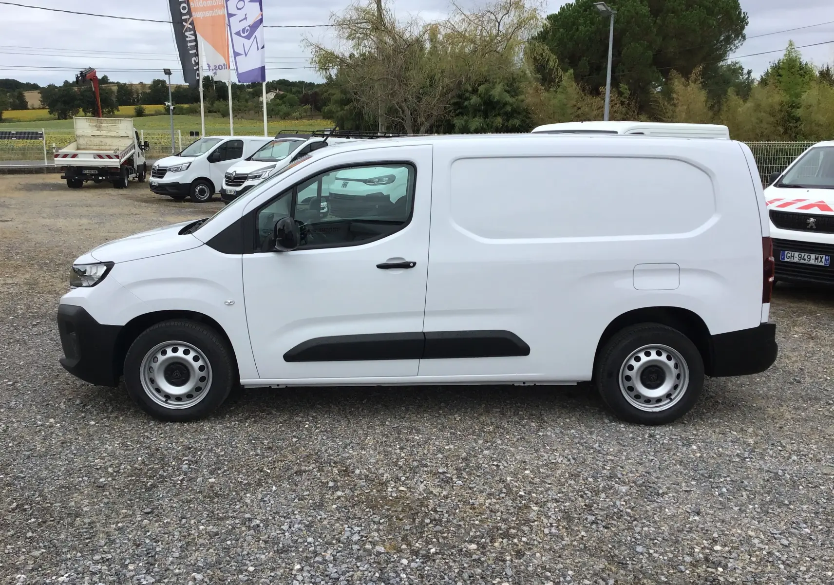 Peugeot Partner blanc en vue de profil côté gauche, utilitaire avec porte latérale coulissante et jantes acier simples.