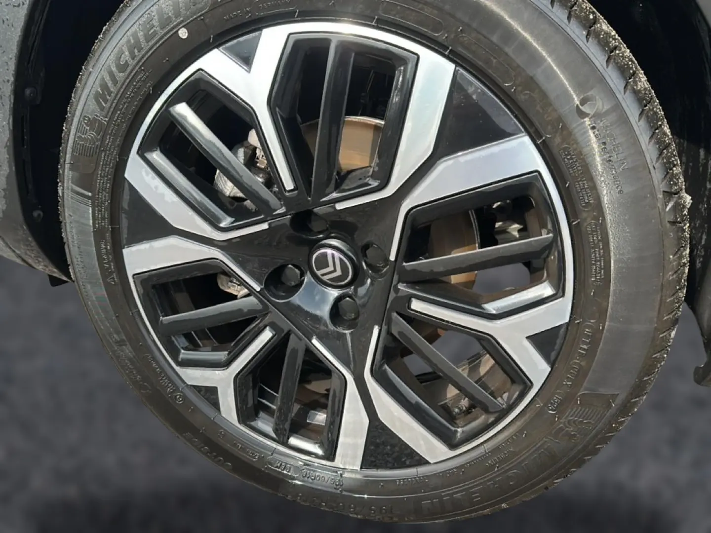 Gros plan sur la jante alu noire et argentée d'une Citroën C4 X noire, vue côté droit.