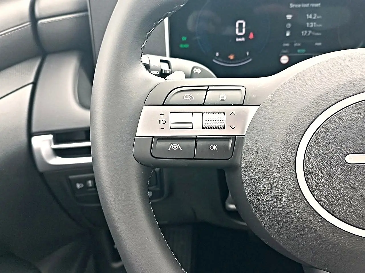 Gros plan sur le volant cuir multifonction gris du Hyundai Tucson 2026 avec commandes intégrées et tableau de bord numérique.