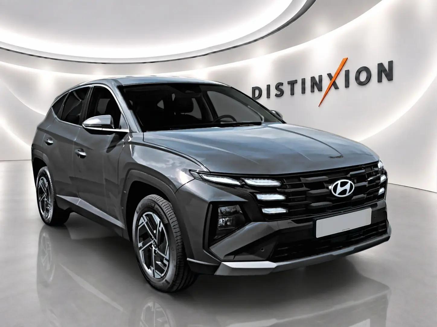 Vue 3/4 avant du Hyundai Tucson 2026 gris ecotronique avec calandre noire et jantes alliage 17 pouces.