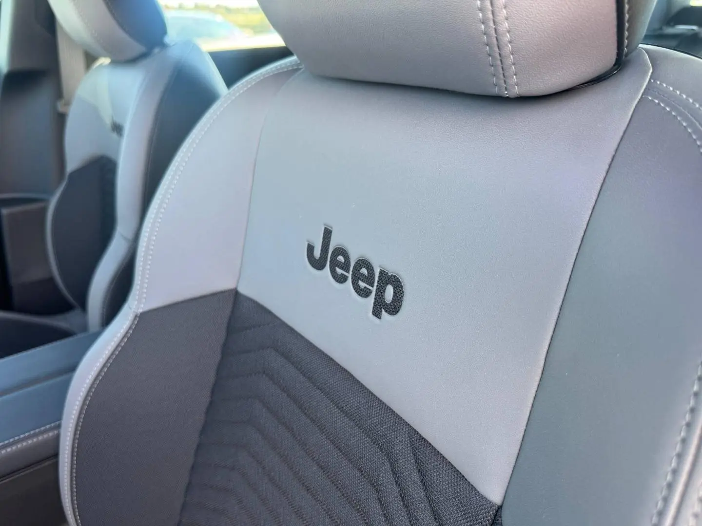 Gros plan sur le siège avant gris anthracite avec logo Jeep brodé, intérieur du Compass 2026.