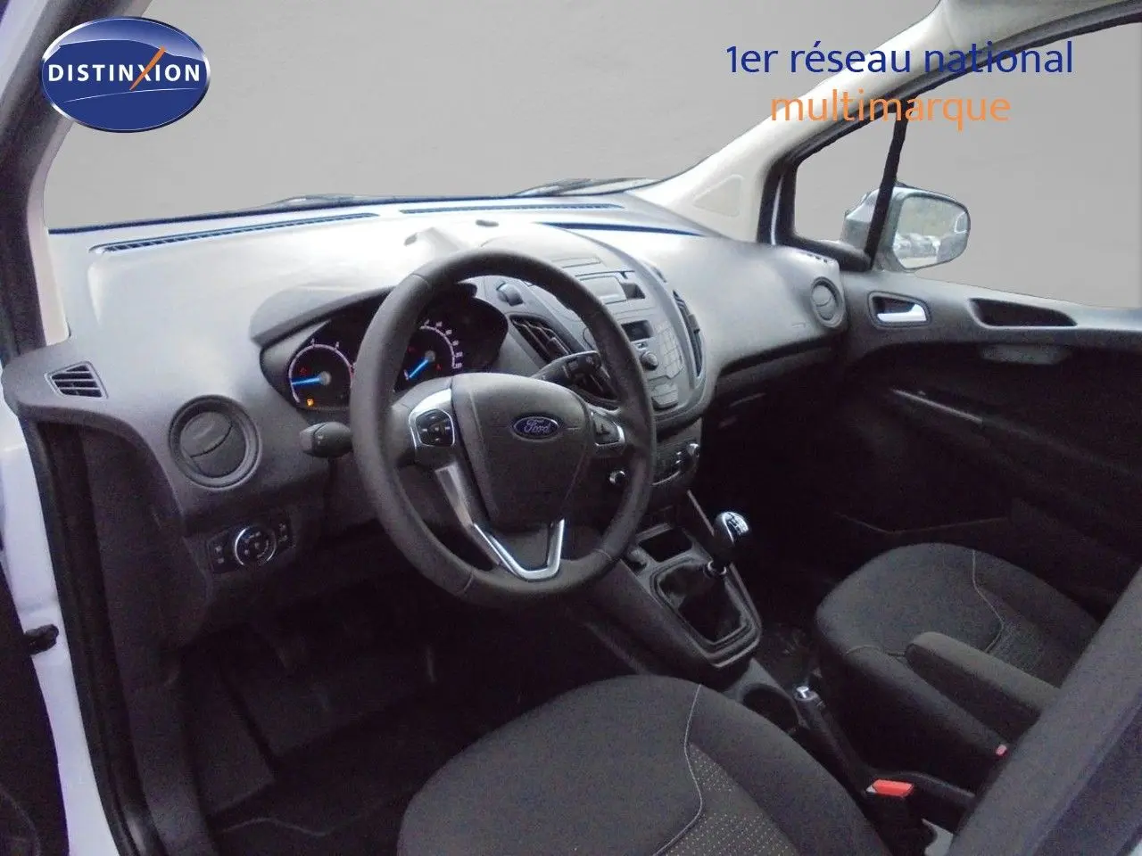 Vue intérieure côté conducteur du Ford Transit Courier blanc glacier 2022, tableau de bord et volant avec boîte manuelle visibles.