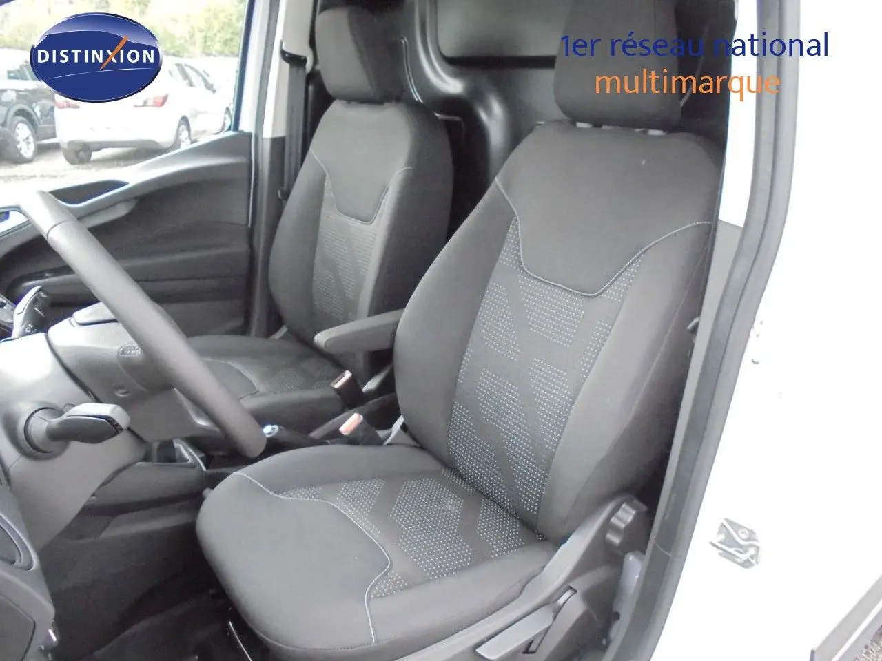 Intérieur du Ford Transit Courier 2022 montrant les sièges avant noirs et la console côté conducteur, porte ouverte côté droit.