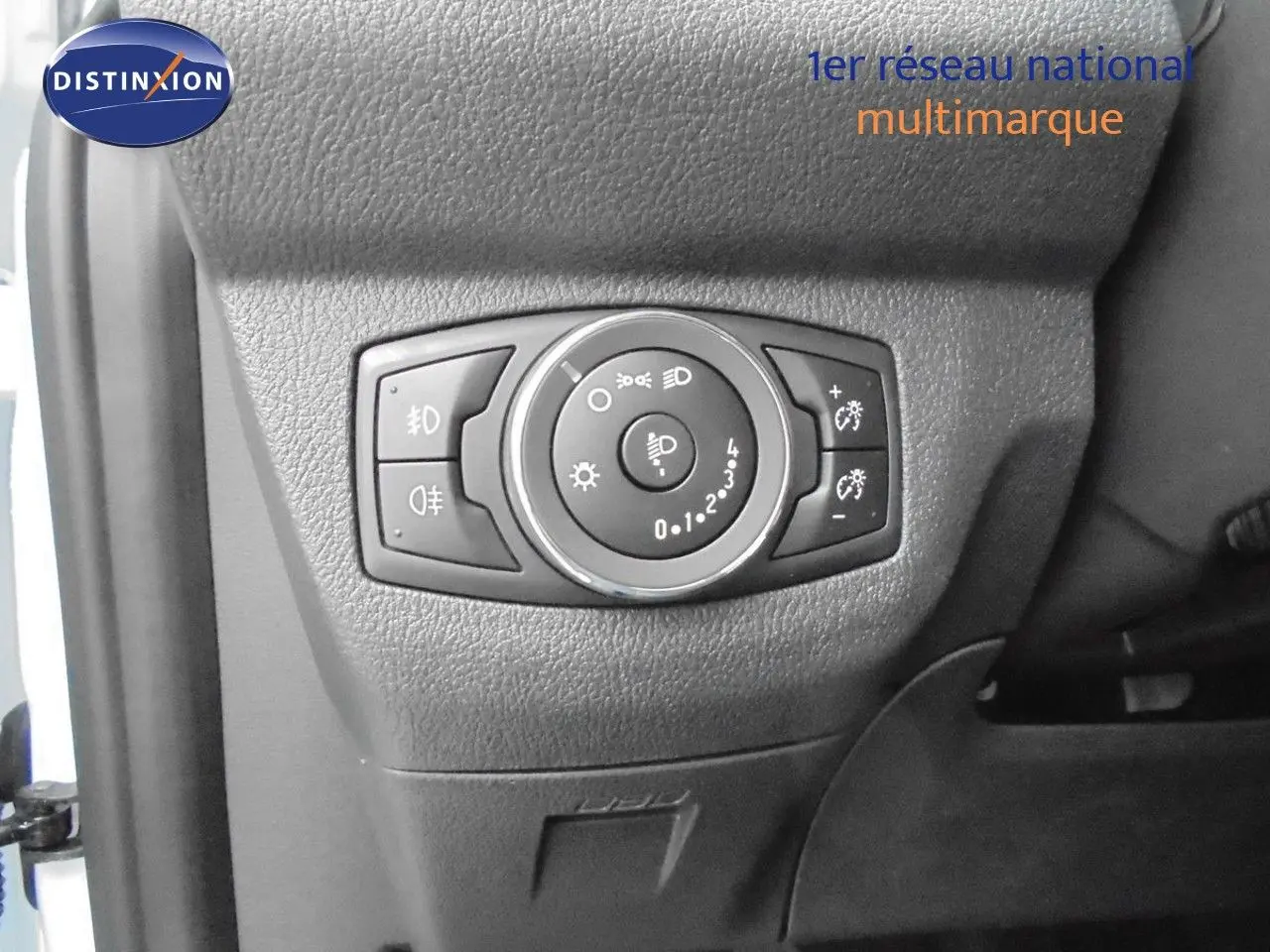 Gros plan sur le panneau de commande des phares du Ford Transit Fourgon Courier blanc glacier, côté gauche intérieur conducteur.