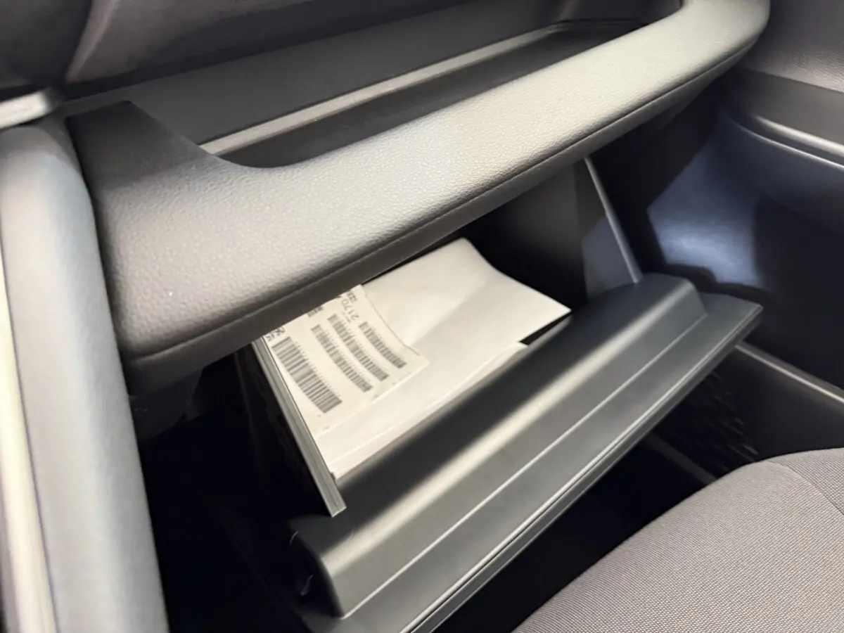 Gros plan sur la boîte à gants ouverte du Toyota C-HR 1.8 Hybride blanc, montrant des documents à l'intérieur.