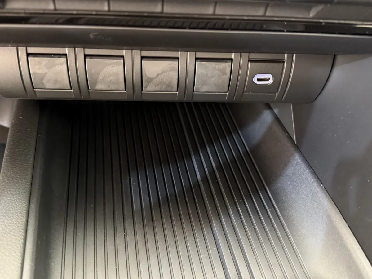 Gros plan sur la console centrale noire du Toyota C-HR 1.8 Hybride 140 Dynamic avec port USB-C visible.