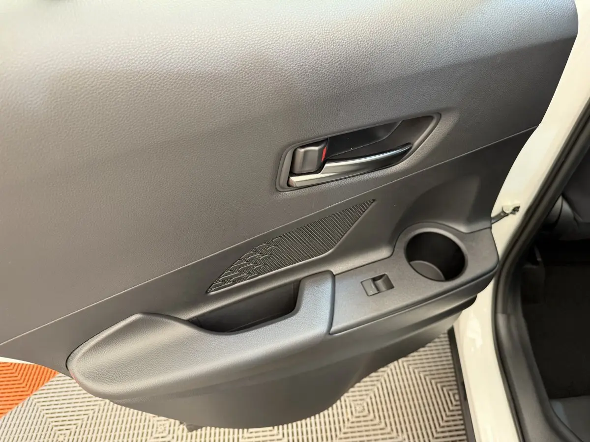 Gros plan sur la porte avant droite blanche du Toyota C-HR 1.8 Hybride 140 Dynamic avec poignée et rangement intégré.