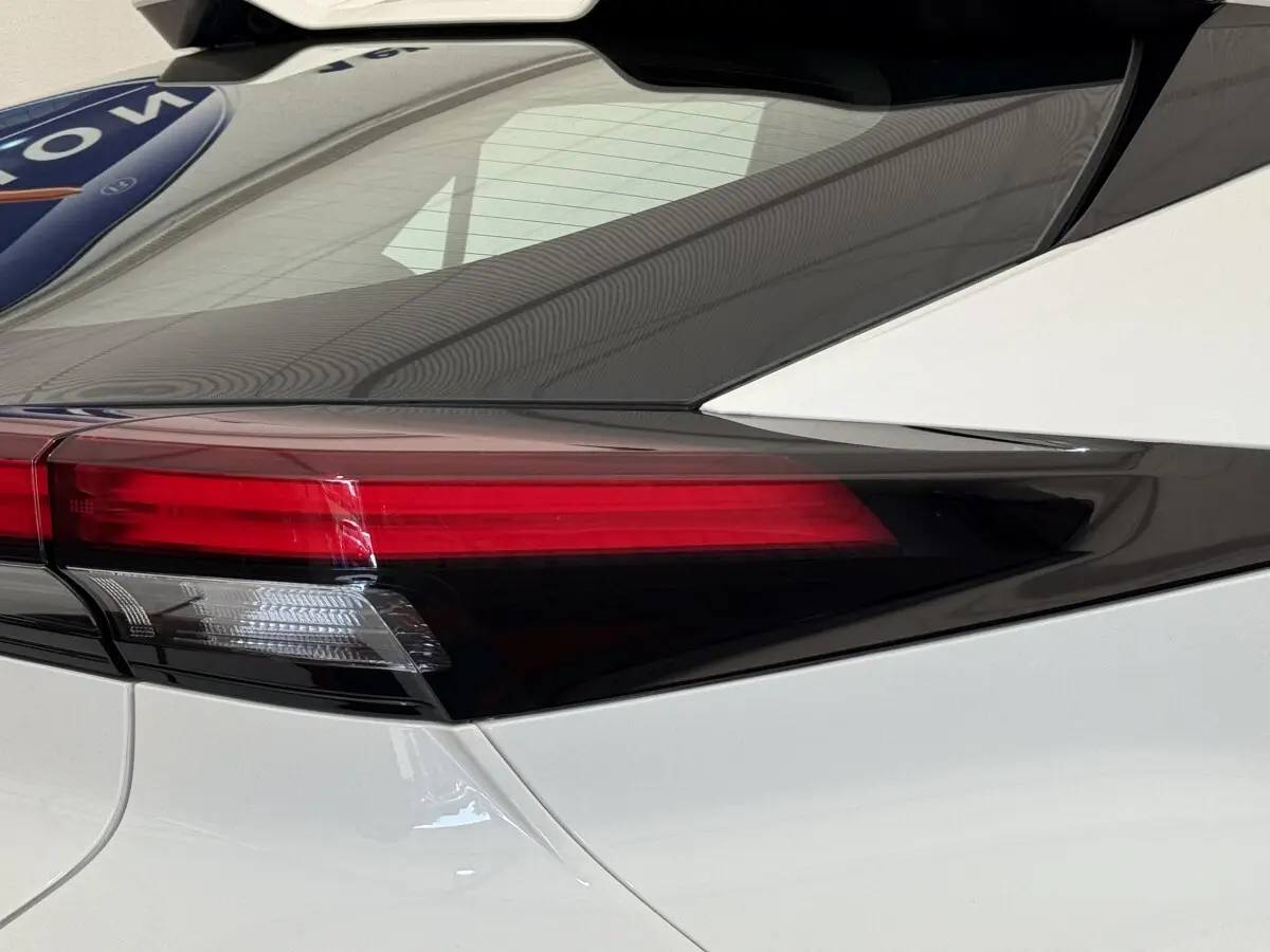 Gros plan sur le feu arrière gauche noir et rouge du Toyota C-HR 1.8 Hybride blanc 2024