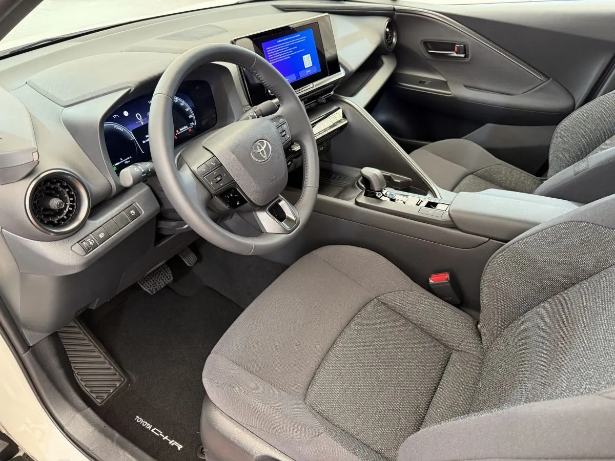 Intérieur avant droit du Toyota C-HR 1.8 Hybride 2024 avec tableau de bord gris et écran tactile central.