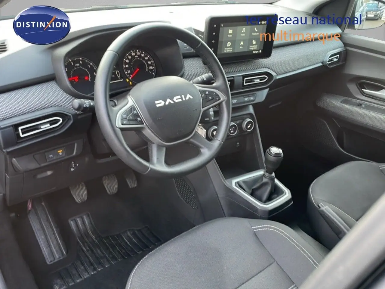 Vue intérieure côté conducteur du Dacia Jogger 2025, tableau de bord gris avec écran tactile et boîte manuelle.