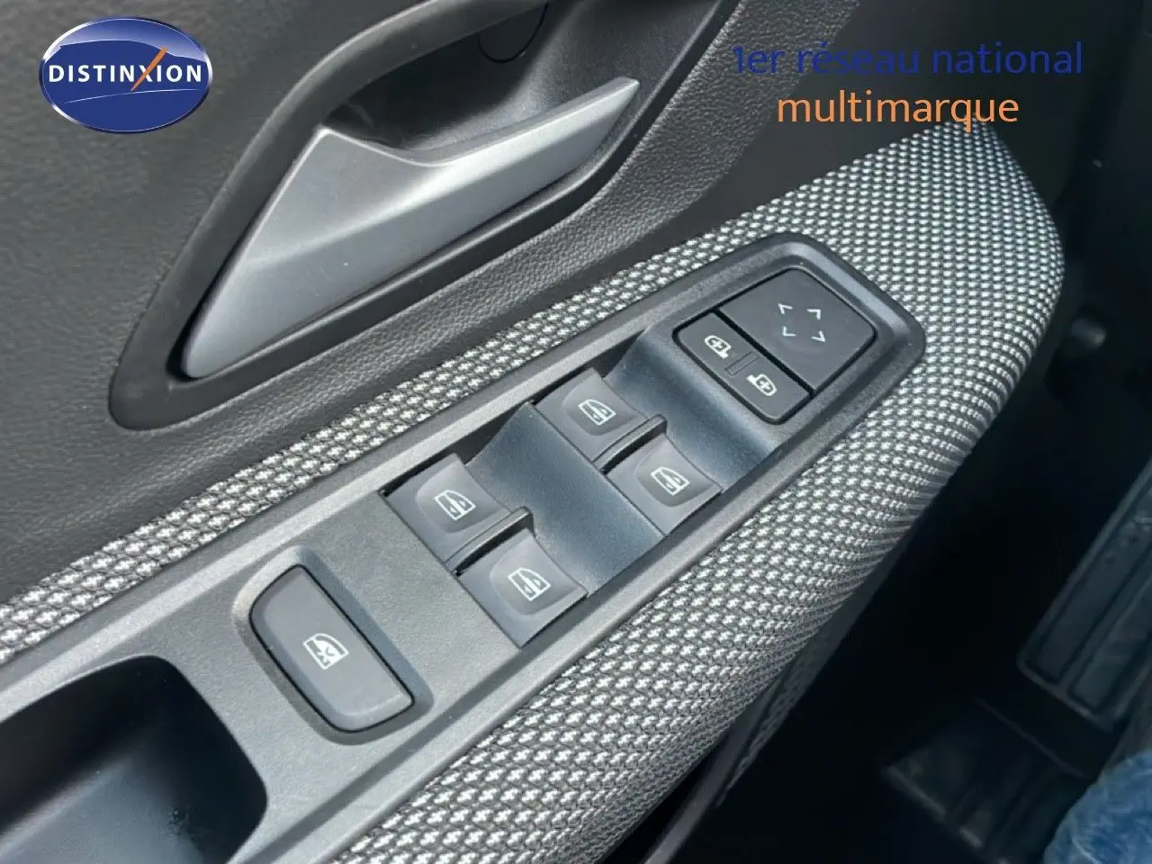 Gros plan sur la commande des vitres côté conducteur avec tissu gris à motifs dans une Dacia Jogger 2025.