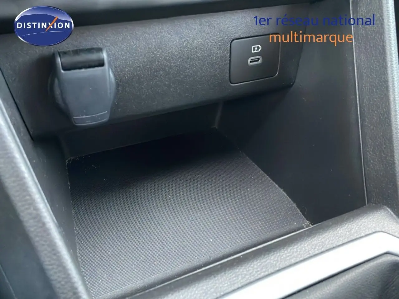 Vue rapprochée de la console centrale noire du Dacia Jogger 2025, montrant un port USB et une prise 12V.