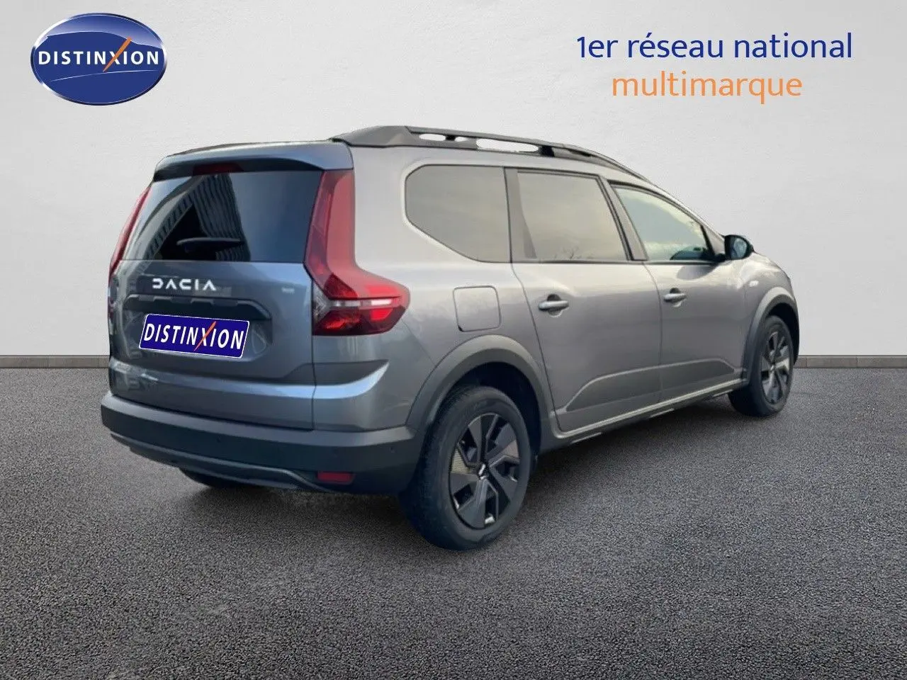 Vue 3/4 arrière droite du Dacia Jogger gris schiste métal, soulignant ses feux arrière en forme de L et ses barres de toit noires.