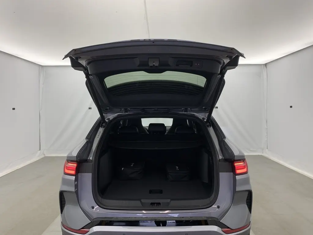 Vue arrière du coffre ouvert du BYD SEAL U Time Grey 2025, avec feux LED allumés et deux sacs noirs à l'intérieur.