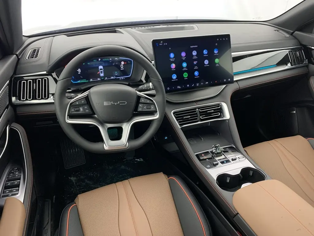 Vue intérieure avant du BYD SEAL U 2025 avec tableau de bord numérique, écran tactile 15,6'' et sièges en similicuir brun.