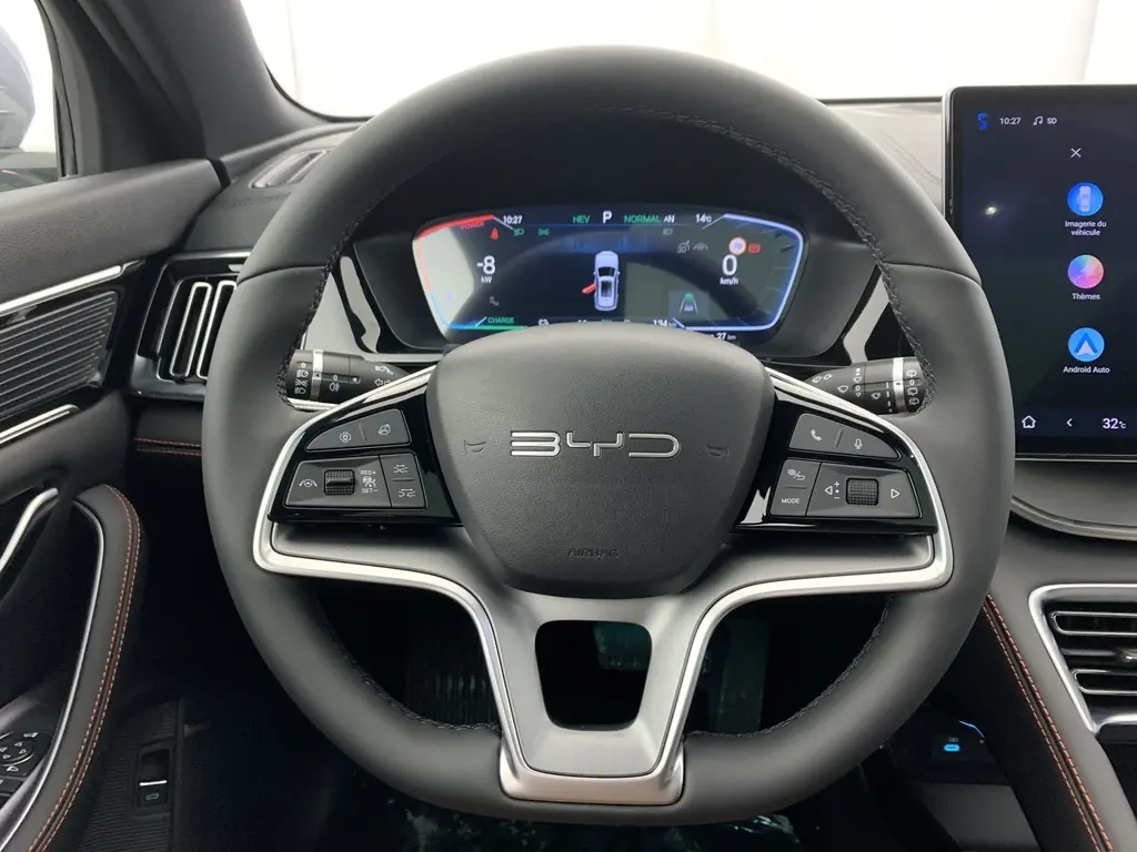 Vue intérieure centrée sur le volant noir du BYD SEAL U 2025 avec tableau de bord numérique et écran tactile latéral.