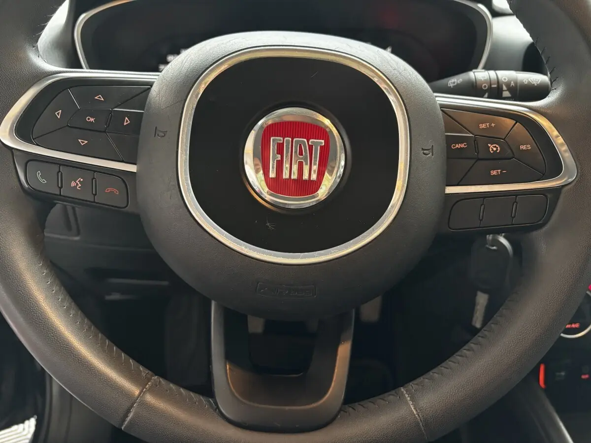 Gros plan sur le volant cuir et alu noir du Fiat Tipo 2017 avec commandes multifonctions intégrées.