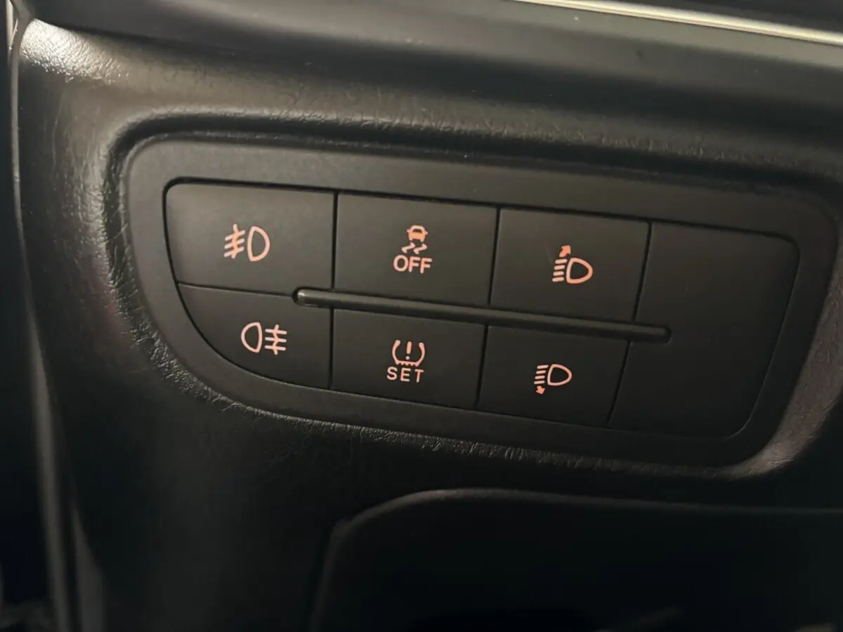 Gros plan sur les commandes d’éclairage et d’ESP du tableau de bord d’une Fiat Tipo noire de 2017.
