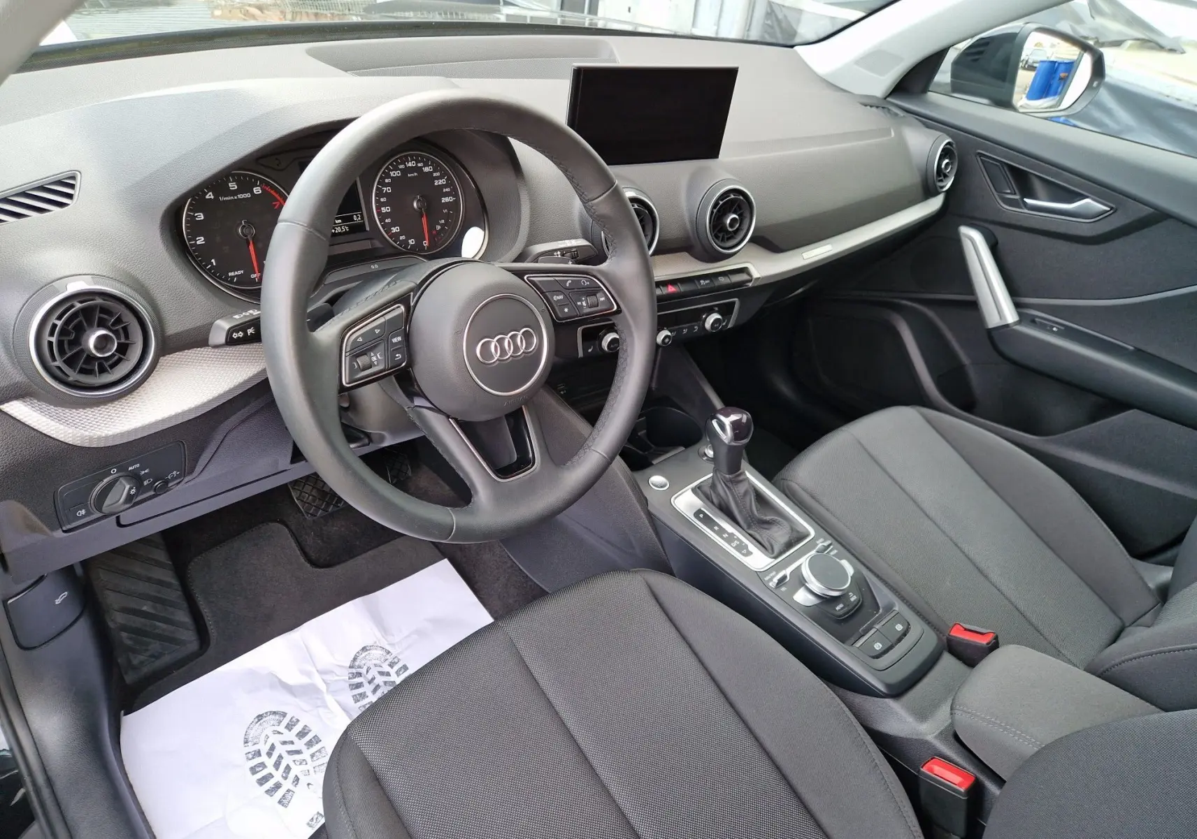 Vue intérieure côté conducteur de l'Audi Q2 35 TFSI 2023 avec volant multifonction et sellerie tissu noir.