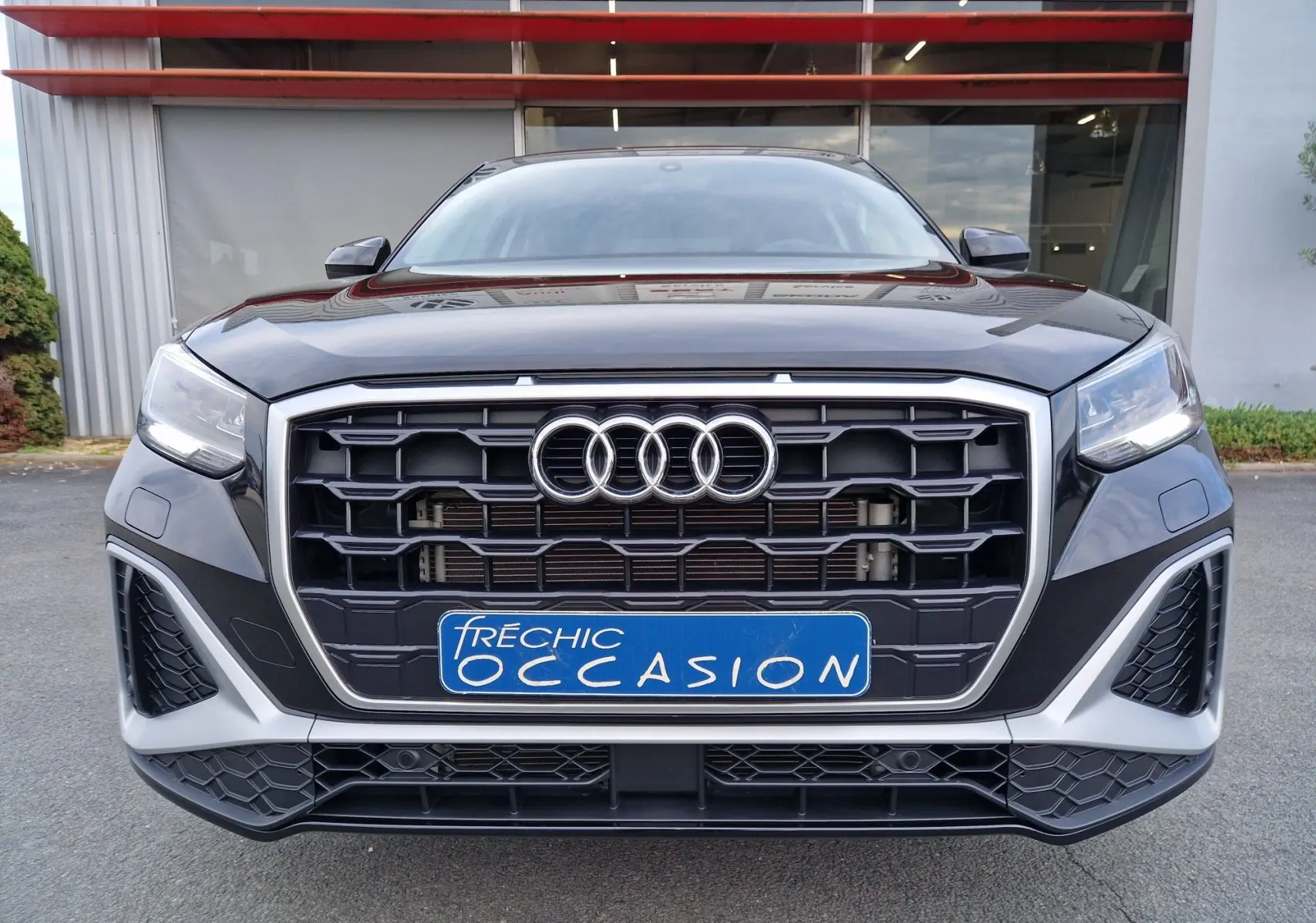 Vue frontale d'un Audi Q2 noir mito metal 2023 avec calandre hexagonale et logo quatre anneaux bien visible.