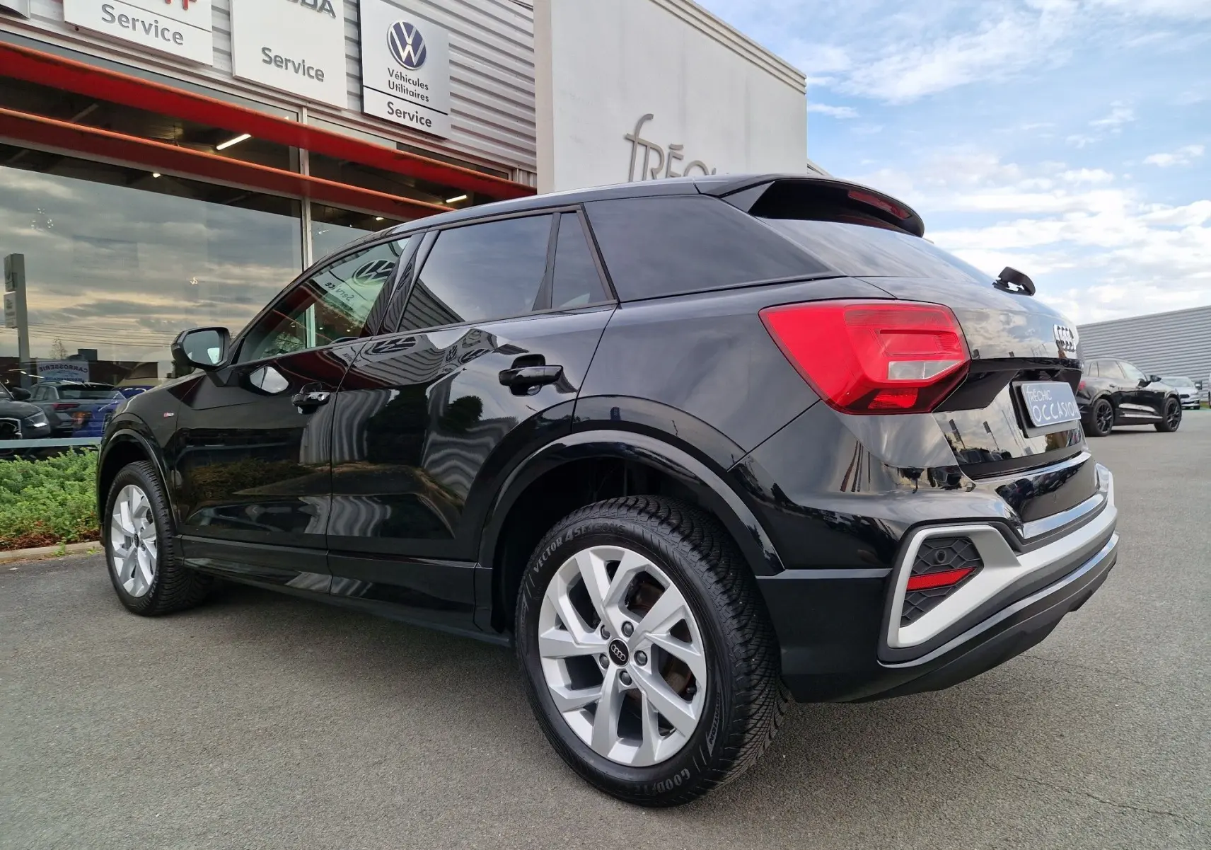Audi Q2 noir mito metal vue 3/4 arrière droit, mettant en valeur ses jantes argentées et feux arrière LED.