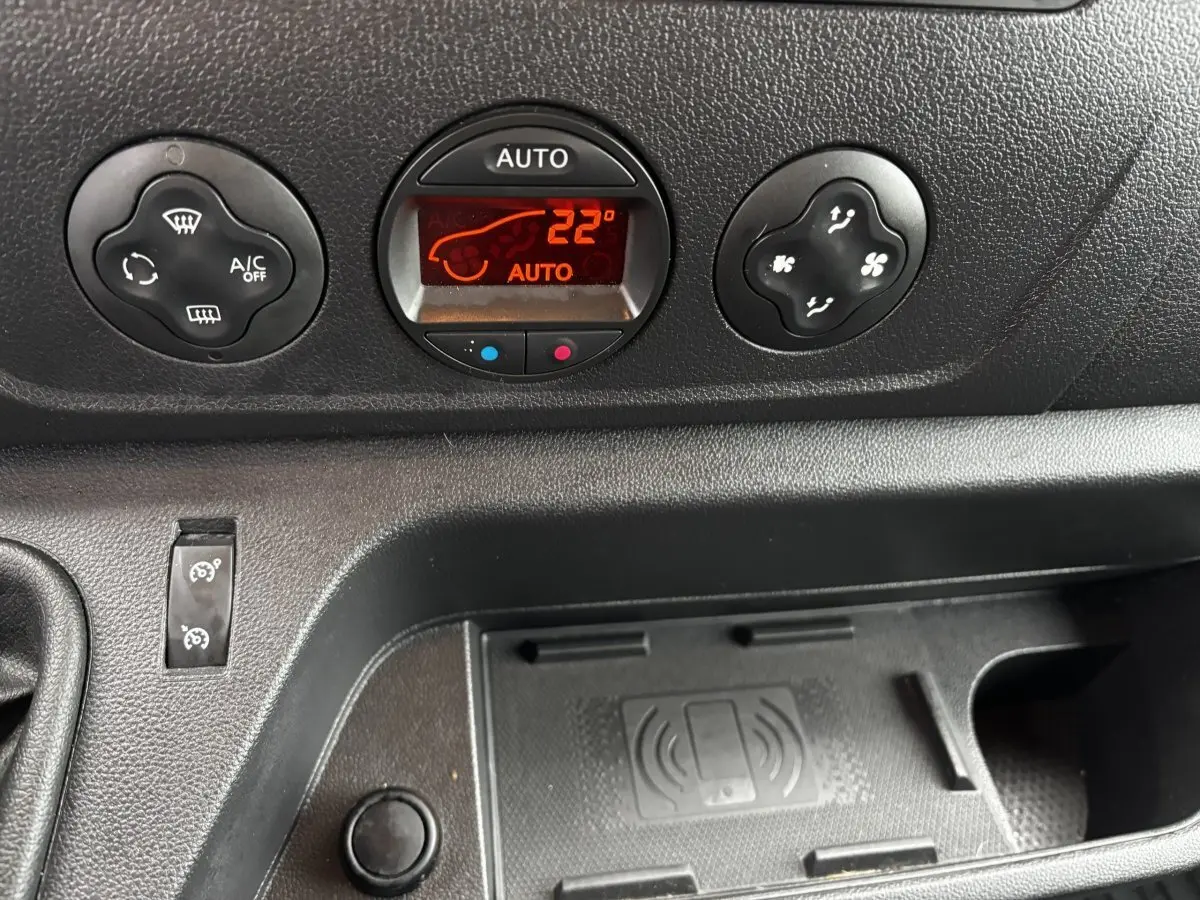 Gros plan sur la console centrale noire du Renault Master 2020, avec commandes climatisation et zone de recharge sans fil.