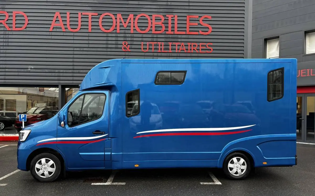 Vue de profil côté gauche d’un Renault Master bleu avec bandes blanches et rouges, vitres latérales et cabine surélevée.