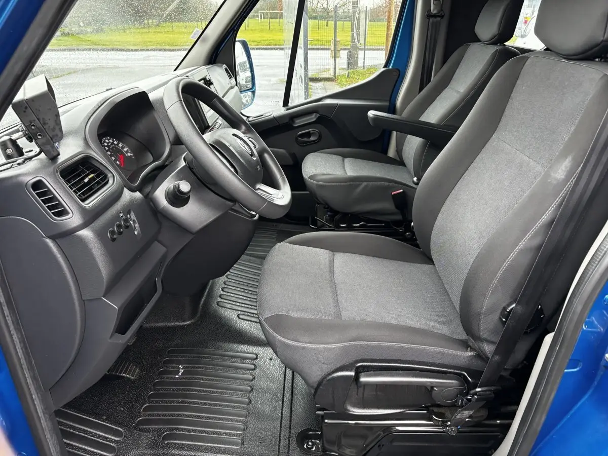 Vue intérieure côté conducteur du Renault Master bleu 2020, montrant les sièges gris et le volant réglable.