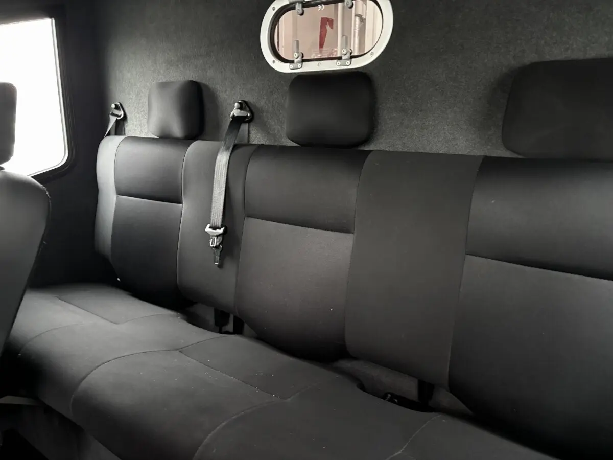 Vue intérieure du côté arrière droit montrant la banquette noire du Renault Master avec une cloison vitrée.