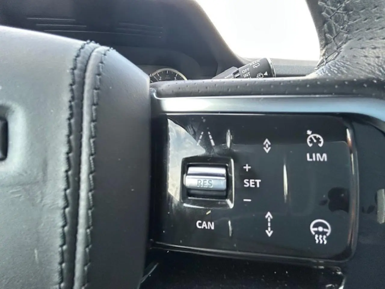 Gros plan sur les commandes de régulateur de vitesse sur le volant cuir noir du Range Rover Evoque gris foncé.