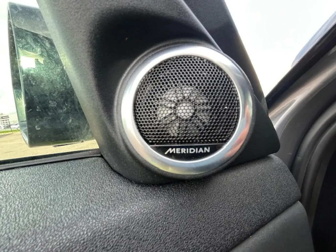 Gros plan sur le haut-parleur Meridian intégré à la porte côté gauche du Range Rover Evoque gris foncé 2022.
