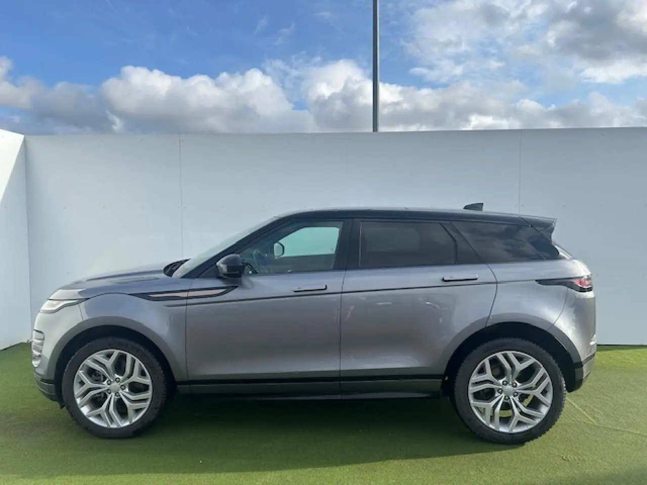Profil droit d'un Range Rover Evoque gris foncé avec toit noir et jantes 20 pouces sur fond extérieur clair.