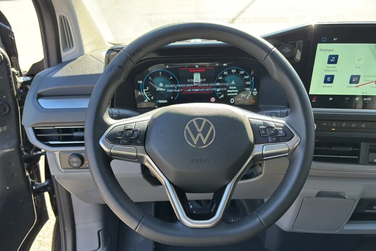 Vue rapprochée du volant multifonctions noir et du tableau de bord digital du Volkswagen Transporter TDI 170 DSG ProCab L1 2026.