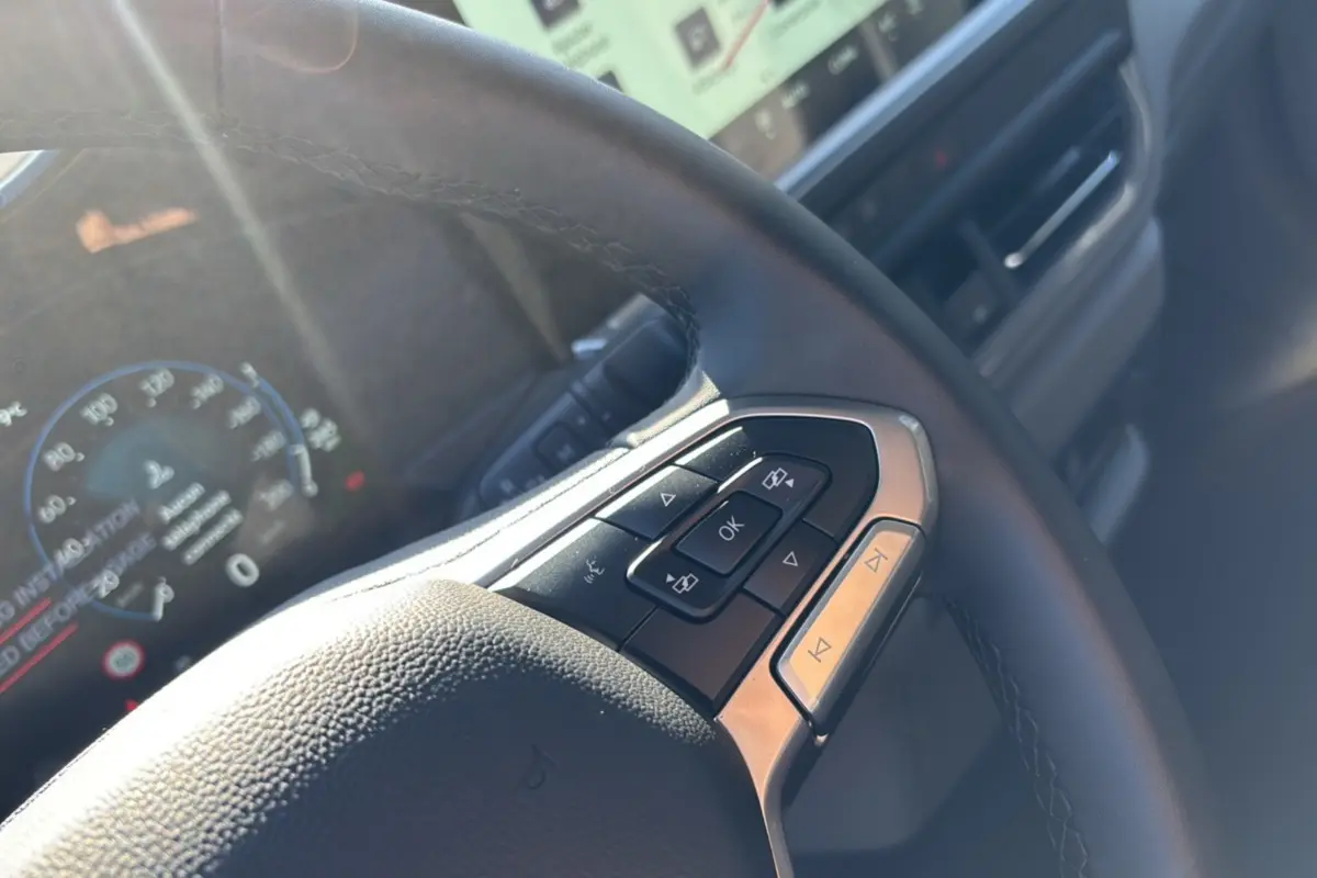 Gros plan sur le volant multifonctions du Volkswagen Transporter TDI 170 DSG Procab L1, avec tableau de bord numérique en arrière-plan.