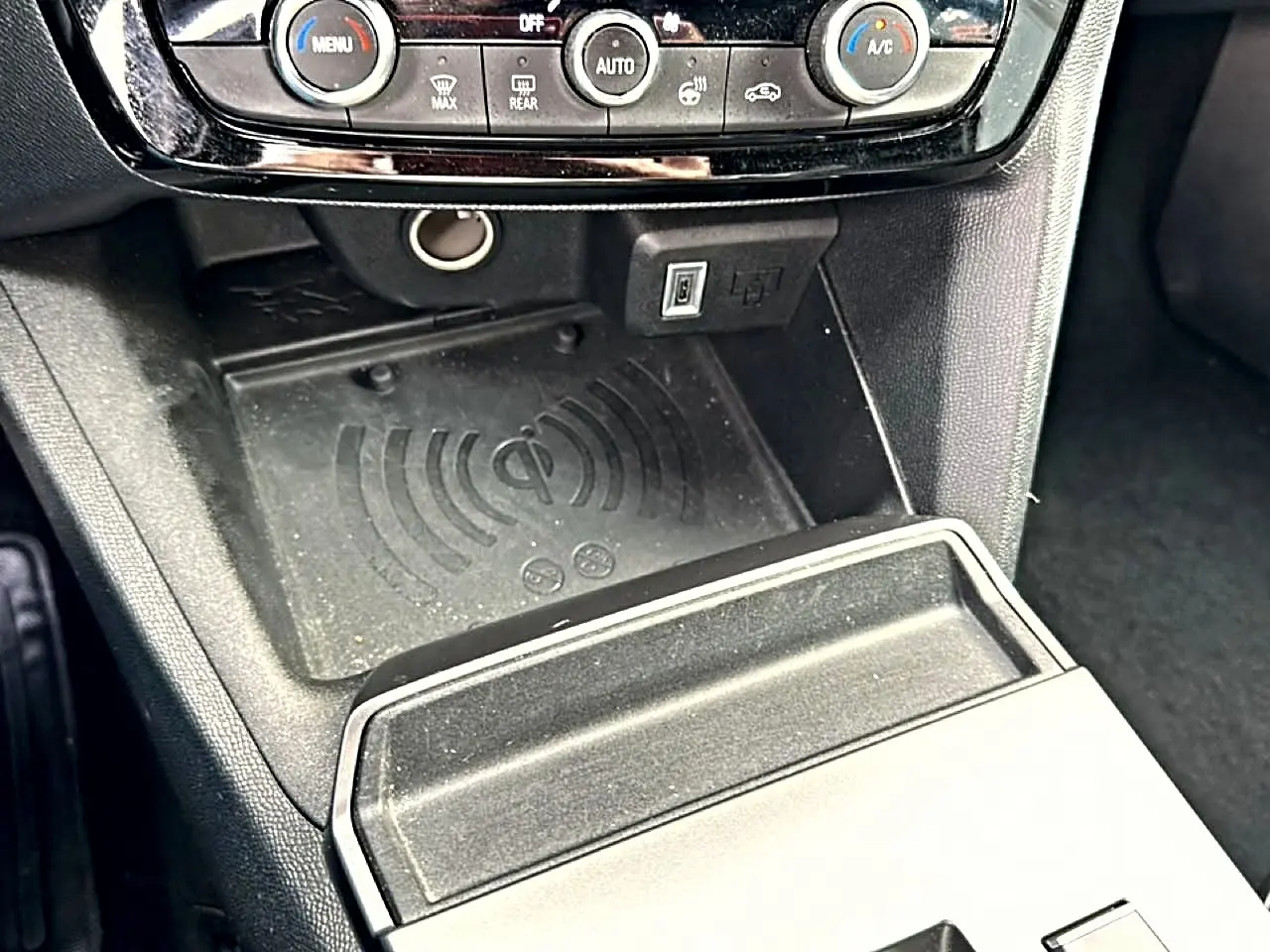 Détail de la console centrale noire de l’Opel Mokka 2025 avec zone de recharge sans fil et commandes de climatisation.