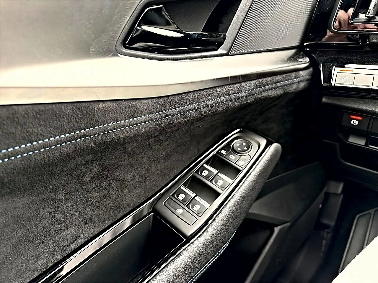 Gros plan sur la porte côté conducteur du Renault Austral gris schiste, avec commandes des vitres et surpiqûres bleues.