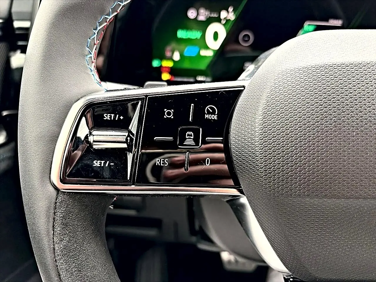 Gros plan sur les commandes noires brillantes au volant du Renault Austral 1.2 e-tech gris schiste, avec surpiqûres tricolores.