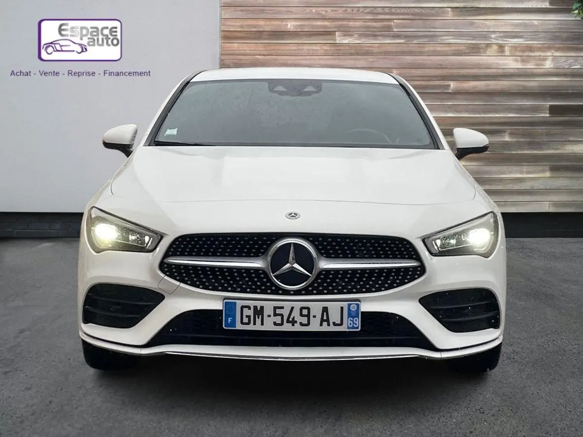 Vue frontale d'une Mercedes Classe CLA Shooting Brake blanche de 2021 avec phares allumés et calandre AMG distinctive.