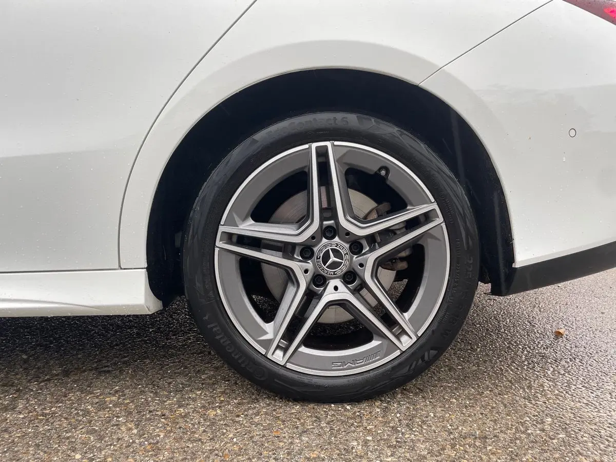 Gros plan sur la roue arrière droite blanche d'une Mercedes Classe CLA Shooting Brake AMG Line 2021 avec jante étoile AMG.