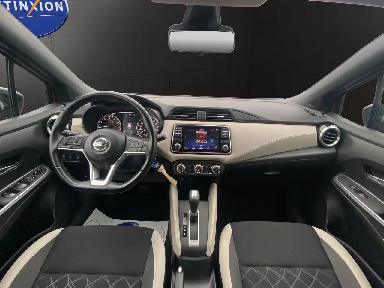 Vue intérieure avant de la Nissan Micra 2022, tableau de bord beige et noir avec volant multifonction et écran tactile central.
