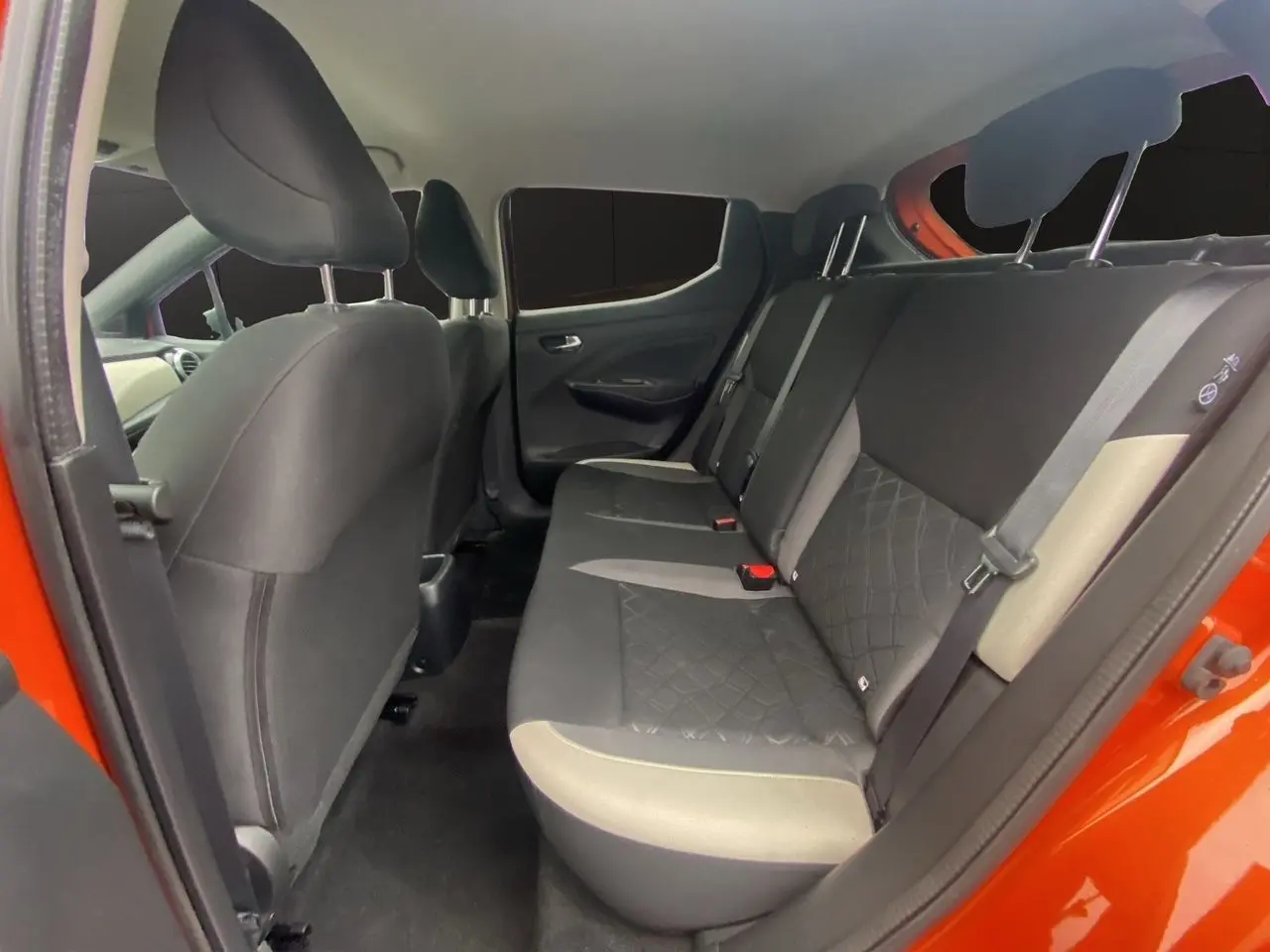 Vue intérieure de la banquette arrière côté droit d'une Nissan Micra 2022 orange Energy avec sièges tissu noir et beige.