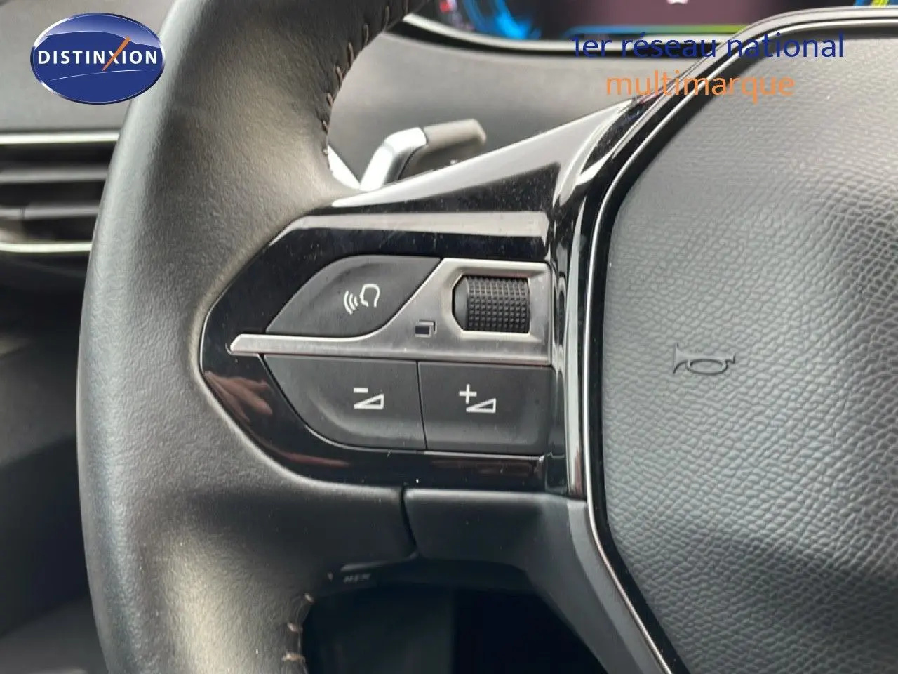 Gros plan sur la partie gauche du volant noir du Peugeot 3008 bleu Célèbes Métal, avec commandes intégrées.