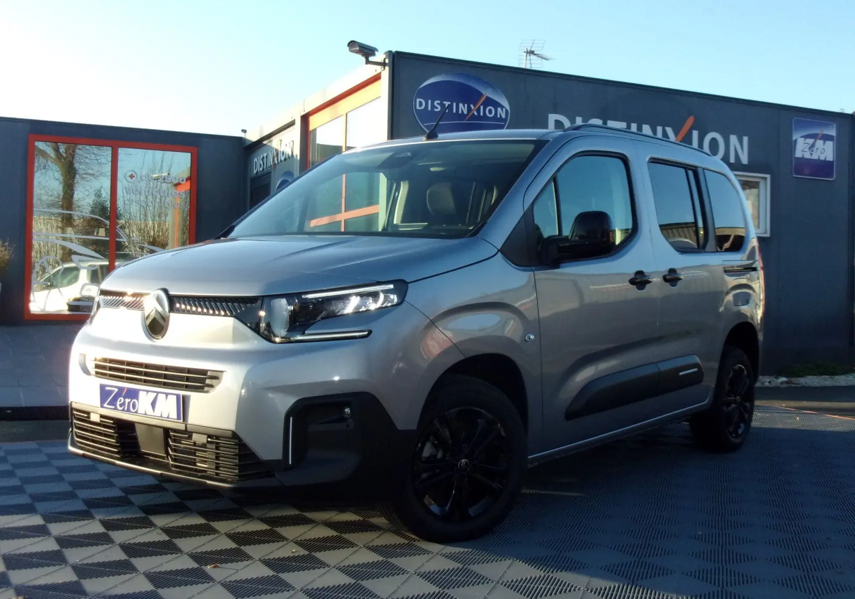 Vue 3/4 avant droite du Citroën Berlingo gris Artense 2025 avec jantes noires et calandre distinctive.