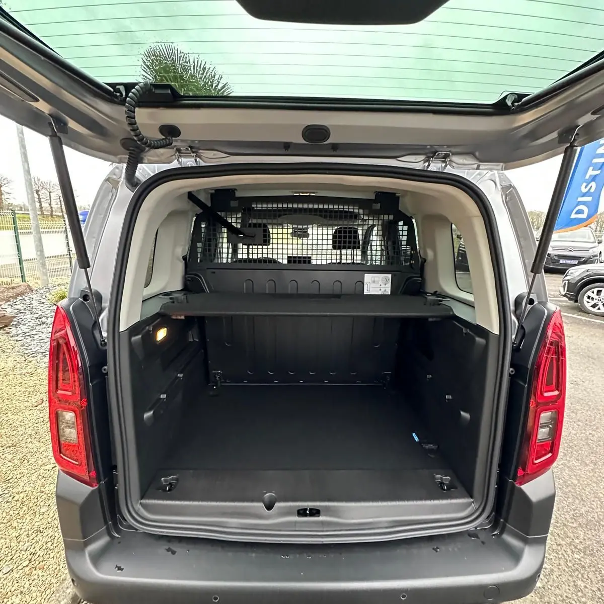 Vue arrière ouverte du Citroën Berlingo gris Artense 2025 montrant le coffre spacieux avec grille de séparation et hayon relevé.