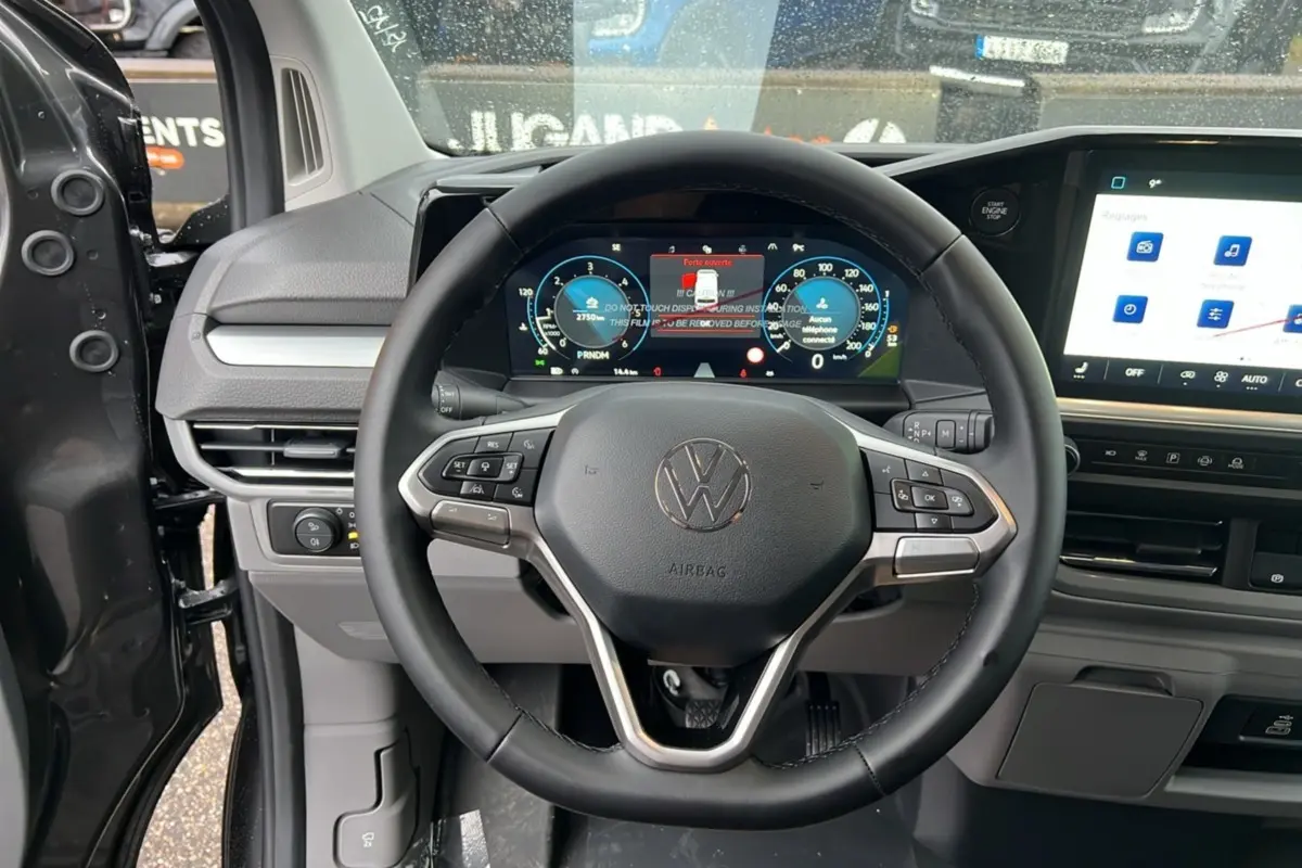 Vue intérieure centrée sur le volant noir et le tableau de bord digital du Volkswagen Transporter TDI 170 DSG 2026.