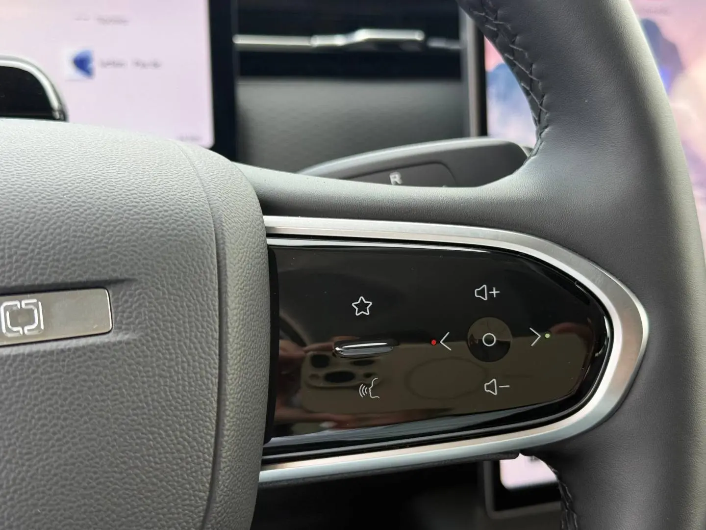 Gros plan sur les commandes tactiles noires du volant côté droit du JAECOO J7 blanc, avec finition chromée.