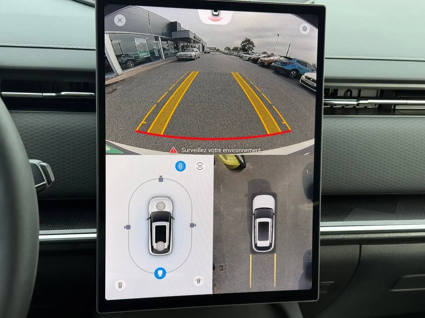 Écran tactile intérieur montrant la caméra de recul et vue 360° du JAECOO J7 blanc en stationnement.