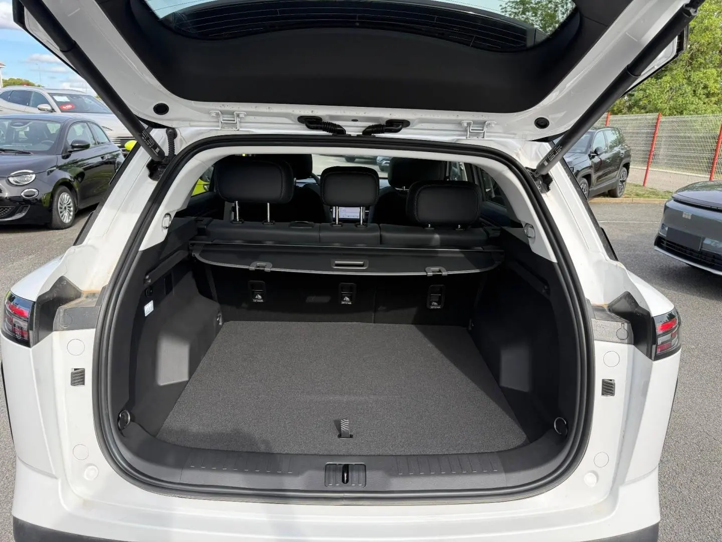 Coffre ouvert vu de l'arrière d'un JAECOO J7 blanc, avec banquette arrière et cache-bagages visibles.