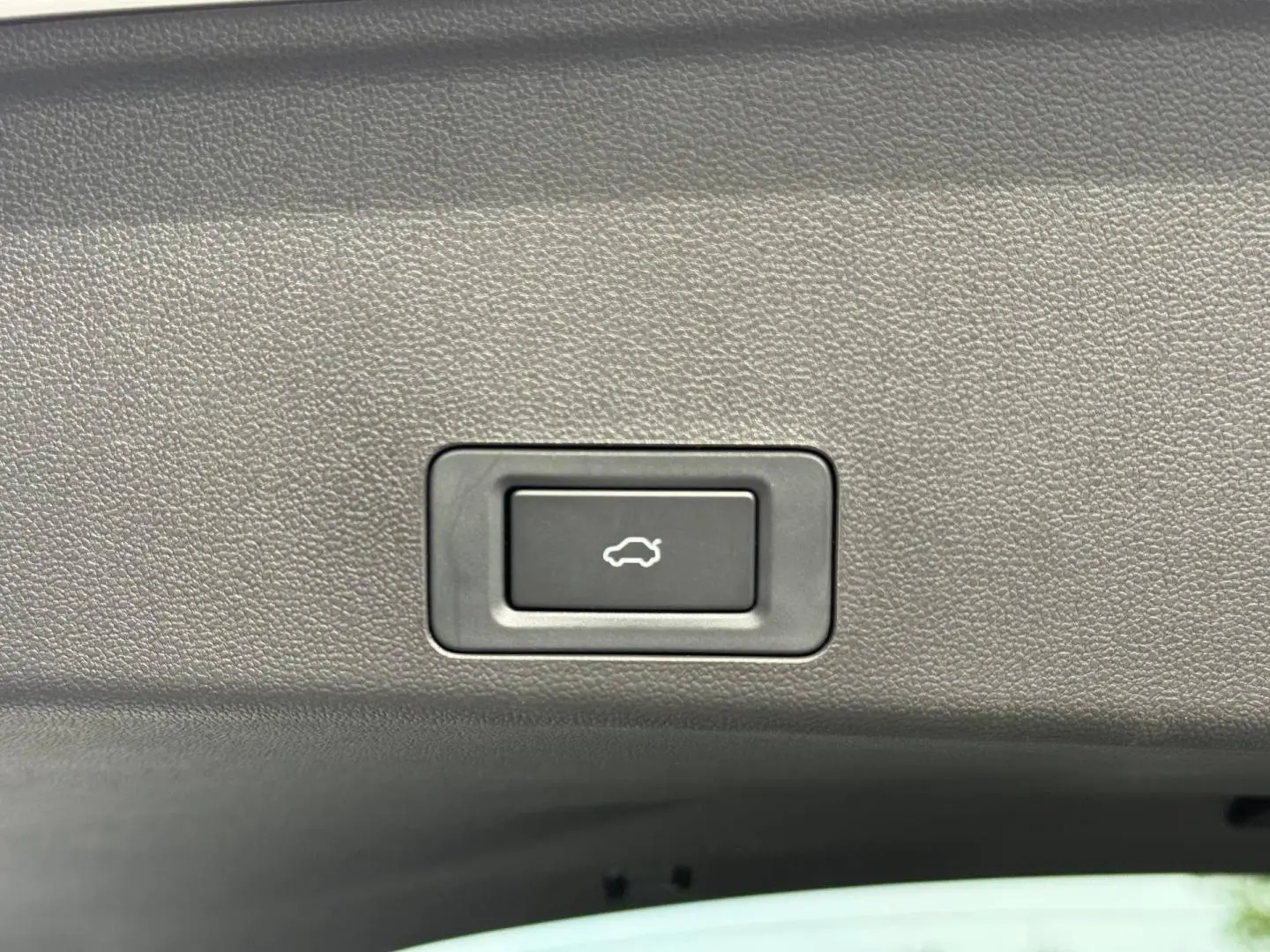 Bouton d'ouverture électrique du coffre sur la garniture intérieure d'un JAECOO J7 blanc hybride rechargeable.